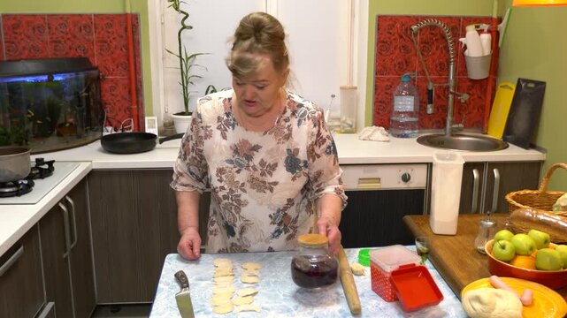 Woman bakes pastries with jam at home.
