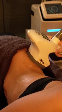 Vacuum roller massage. Lymphatic drainage stage. Dim atmospheric warm light. Masseuse massages woman's sides with a device. self-care, care, weight loss