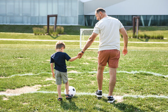man with child playing football outside on field