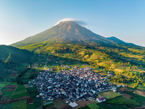 Aerial view of the village of Kejajar at the foot of Mount Sindoro in the Tambi tea plantation area, with terraced fields and a lenticular cloud in Kejajar, Central Java, Indonesia.