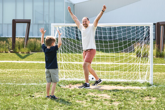 man with child playing football outside on field