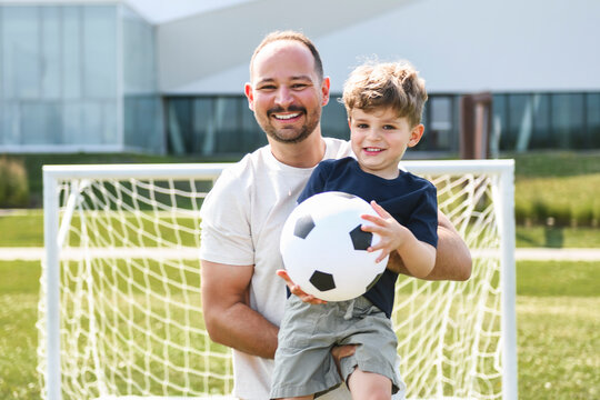 man with child playing football outside on field