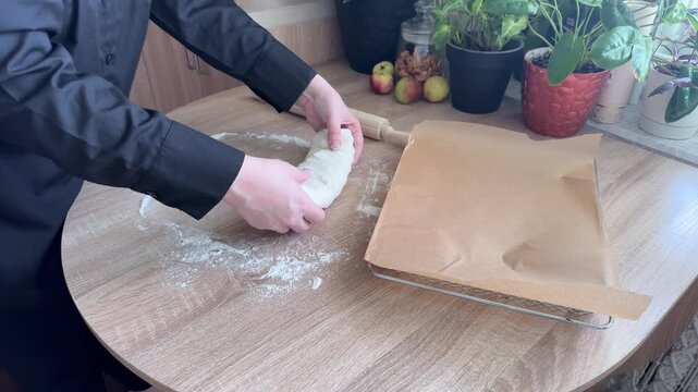 Transferring unbaked homemade apple strudel onto a baking tray before baking