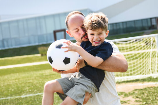 man with child playing football outside on field