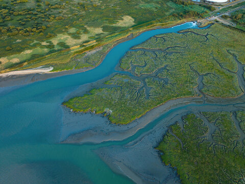 Aerial view of the Fawley Refinery outfall and surrounding wetland area with winding tidal channels and green marshland in Southampton, England, United Kingdom.