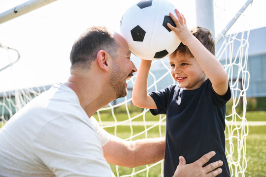 man with child playing football outside on field