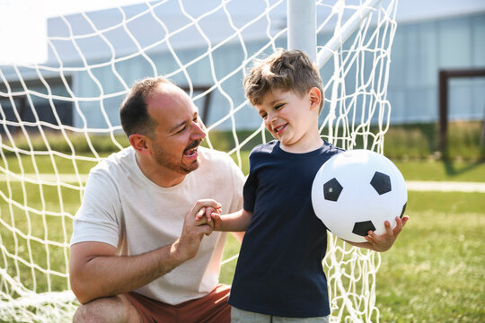 man with child playing football outside on field