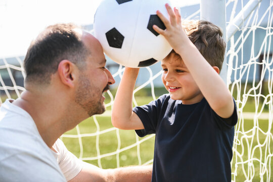 man with child playing football outside on field