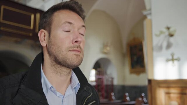 Man seeking peace in a church, sitting in a wooden pew to pray, surrounded by silence and soft natural light.