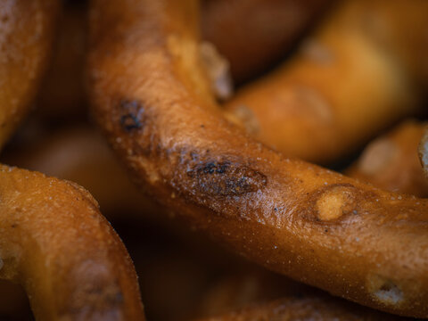 Macro close up shot of a crunchy salted baked pretzel surface with golden brown texture and salt grains