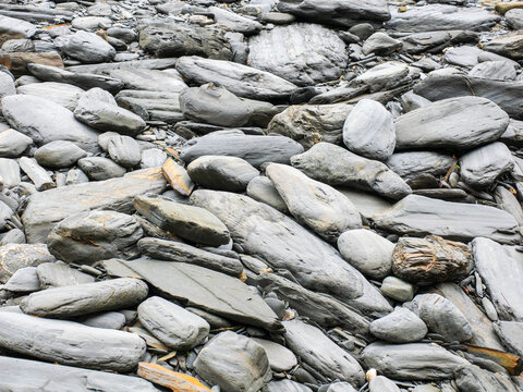 grey black shale rocks and pebbles stones on the shoreline in the UK