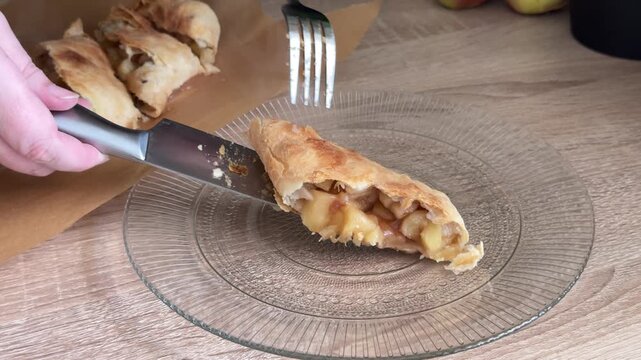 Serving a slice of freshly baked hot apple strudel with visible steam and apple filling