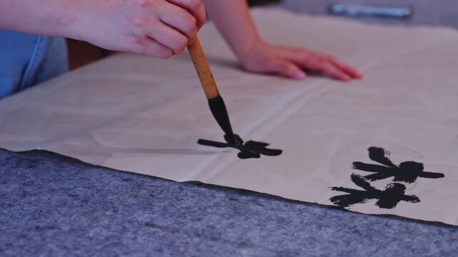Holding paper with both hands and writing large black Chinese characters with a brush