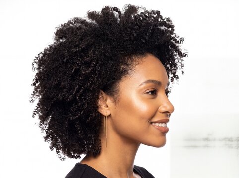 Side profile portrait of a smiling young African American woman with natural curly afro hair against a white background