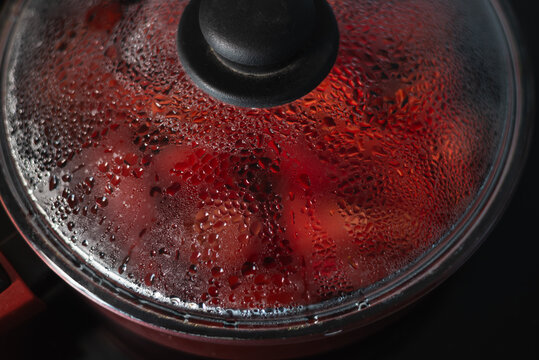 Steam rises from a pot as food cooks inside. The lid is covered in condensation, indicating a warm cooking environment