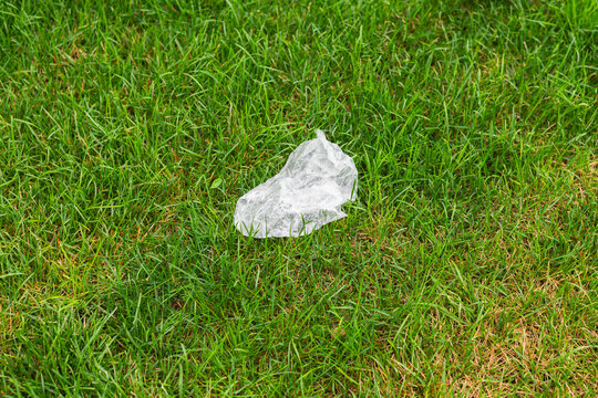A piece of plastic waste lies on a grassy field, showing the impact of littering on natural spaces.