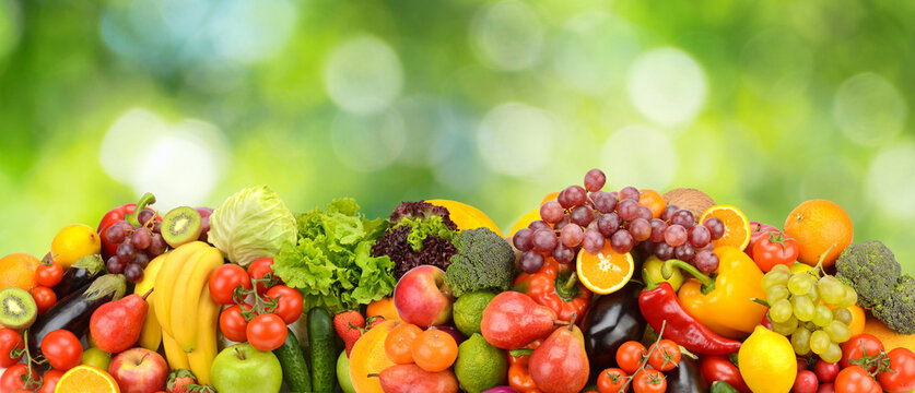 Panoramic Banner Layout of Fresh Farm Vegetables and Assorted Organic Fruits Set Against Bright Green Natural Bokeh Background with Room for Text above Healthy Food Concept