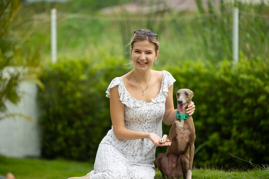 young caucasian woman embraces her gray Italian Greyhound dog, appearing relaxed and content. Home pets. woman holding and hugging her cute dog while walking in the park Outdoor
