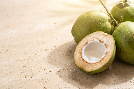 Fresh young green coconuts with opened coconut on cream stone background and copy space