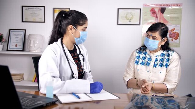 Female doctor sanitizes her patient while their faces covered with protection masks. Indian medical practitioner taking precautions during Coronavirus / COVID-19 outbreak in the hospital - medical ...