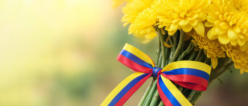 Yellow chrysanthemum bouquet tied with colombian tricolor ribbon, flower festival tribute in medellin, silletero parade heritage, floral culture, orchids, chiva bus, classic festivities copy space
