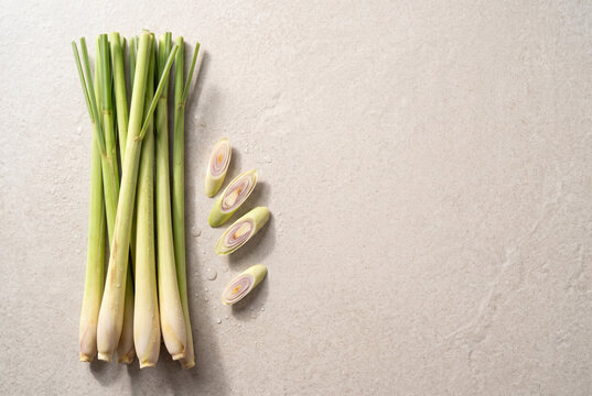 Fresh Thai lemongrass stalks with cut sections on light stone background and copy space