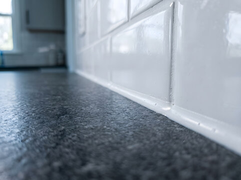 professional kitchen countertop sealant application | white subway tile backsplash with dark granite | waterproof silicone caulking in modern kitchen | home renovation bathroom tile details