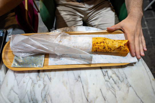 Istanbul, turkey. August 2, 2025. A person holds a street food durum kebab wrap, featuring savory meat and lavash, served on a tray in istanbul