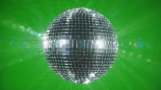 Sparkling mirror disco ball rotating slowly on a solid green screen background with bright light reflections and shimmering highlights