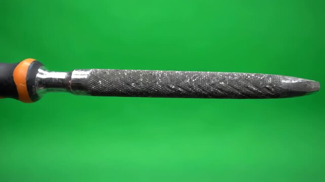 Steel bastard file tool rotating slowly on a bright green screen background for chroma key compositing