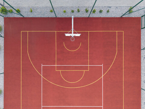 Aerial view of a vibrant red basketball court with yellow markings and a hoop in Krakow, Lesser Poland Voivode, Poland.