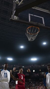 Basketball Player Dunking the Ball Below the Hoop in a Packed Arena
