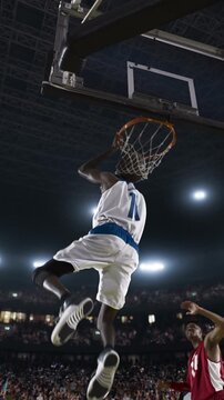 Basketball Player Dunking the Ball as a Defender Watches in a Packed Arena