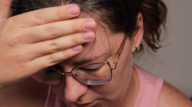 woman tapping forehead with fingers, close up of tired female in glasses doing self massage with closed eyes, headache relief technique at home, concept of mental health, stress therapy, wellness  