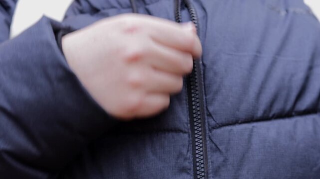 hand zipping up navy puffer jacket, close up of person fastening warm winter coat before going outside, quilted outerwear detail in daylight, concept of clothing store, winter fashion, outdoor apparel