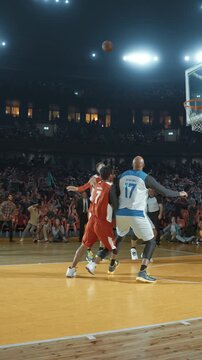 Basketball Players Following a Shot Toward the Hoop in a Packed Arena