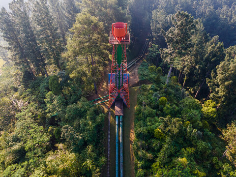 Aerial view of the Ketenger surge tank structure surrounded by dense forest and lush green trees in Baturaden, Central Java, Indonesia.
