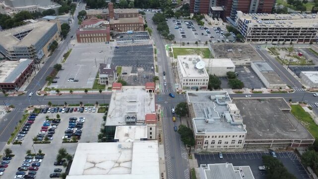 Downtown business district thoroughfares bisect commercial blocks featuring surface parking lots. Paved intersections connect municipal buildings overlooking urban sectors in San Antonio, TX