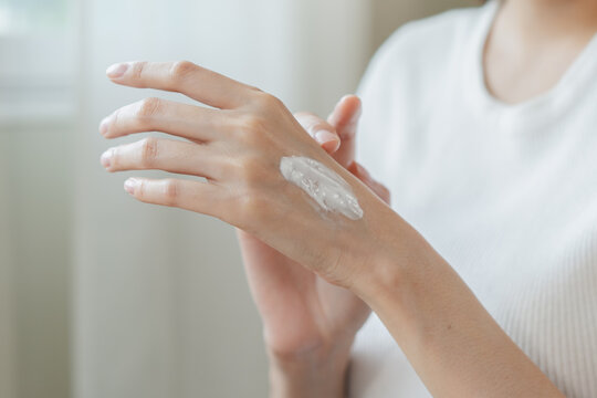 Health skin care, beauty smile asian young woman, girl  hand applying, putting moisturizer on her arm, shoulder after shower bath at home. Skin body cream moisturizing lotion, routine in the morning.