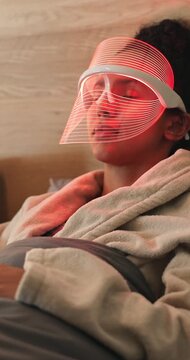 Beauty, mask and woman with red light therapy on bed in home for skincare, relax or wellness. Health, calm and person with infrared LED treatment for dermatology with collagen production in house.