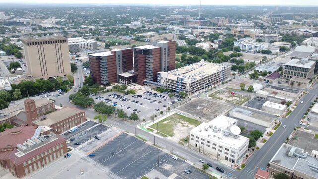 Downtown business district asphalt lots intersect structured parking facilities near corridors. Multi-story office buildings overlook municipal thoroughfares in historic San Antonio, Texas