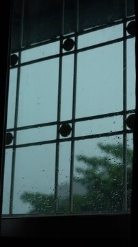 Window View from Inside Room Looking at Heavy Rain and Lightning Flash with Water Droplets on Glass