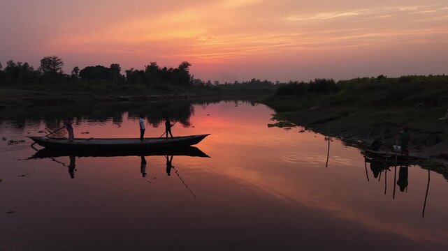 Serene sunset over tranquil river with silhouette of people in a traditional wooden boat and