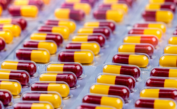 Close up of red and yellow pharmaceutical capsule medication in blister packs, healthcare and pharmacy background for prescription medicine, hospital treatment and pharmaceutical industry concept.