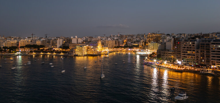 Aerial view of Balluta Bay and Karmnu church lights on the sea at dusk