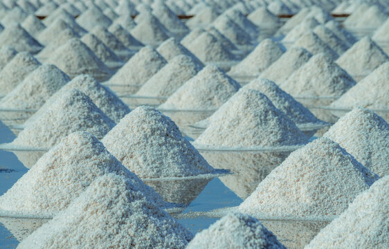 Sea salt piles in traditional salt farm during solar evaporation process for natural sodium chloride production and sustainable mineral harvesting in Thailand. Organic sea salt crystallization.