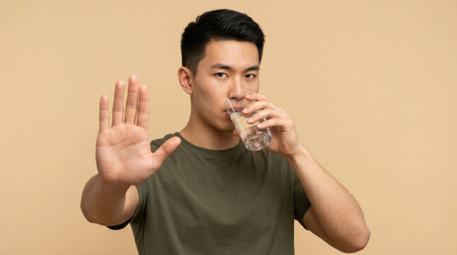 Young Man Refusing Alcohol While Drinking Water Against Beige Background