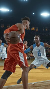 Basketball Player Dribbling Past a Defender in a Packed Arena