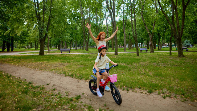 Confident young girl rides bicycle hands free after mastering balance. Concept of independence milestone, self confidence, childhood achievement.