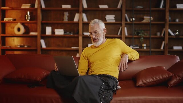 Middle-aged man in trendy clothing talking with a friend during a video call